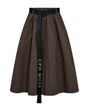 Load image into Gallery viewer, CMKENDY-SKIRT is a lightly woven skirt in a fabric with a crisp structure and a modern, sporty attitude. The A-shaped silhouette is paired with a fixed waistband with belt loops and a distinctive logo belt with metal D-rings for a refined utility-inspired look. Closes with a hidden zipper in the side seam. The skirt is fully lined for added comfort and structure and has a flattering midi length.




Lightweight woven quality with crisp texture
A-shaped silhouette
Fixed waistband with belt loops
Statement be