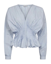 Load image into Gallery viewer, CMPOPLIN-BLOUSE is crafted in crisp woven cotton poplin with a sculptural silhouette. The deep V-neckline is balanced by voluminous long batwing sleeves with buttoned cuffs. The fully pleated waist enhances and defines the shape. A pleated peplum hem adds movement and a refined architectural finish, completed with an invisible zipper in the side seam.




Woven cotton poplin with a crisp handfeel
Deep V-neckline
Pleated waist for a defined silhouette
Voluminous long sleeves with buttoned cuffs
Invisible zip