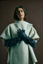 Load image into Gallery viewer, CMWOON-CAPE is an oversized cape in a heavy brushed wool mix, offering a sculptural drape and a clean, minimal expression with an asymmetrical front snap button closure and integrated collar scarf

Heavy woven wool mix with soft brushed surface
Oversized cape fit
Asymmetric closure with integrated scarf collar
Loop and strap detail in side seams
Back length in size S/M is 75 cm. All measurements are indicative and may vary