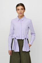 Load image into Gallery viewer, Chin Shirt from Créton

Details

Classic shirt collar and hidden button closure
Decorative bows at the waist as an integral part of the design
Slightly cropped length with volume at the hip
Long sleeves with cuffs
Smooth and light structure with an elegant look

Styling
A modern shirt with a feminine twist. The distinctive bows add a playful and stylish expression that elevates an otherwise classic design. Style it with wide trousers for a trendy look, or combine with a skirt for a more elegant and feminine