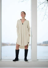Load image into Gallery viewer, A feminine dress designed with a flattering curved hem and extra length at the back for a graceful silhouette. The V-neckline is finished with a small collar finish, while small slits at the sleeves add a elegant touch.
Thoughtful details include practical pockets and signature grosgrain band accents that highlight the brand design. Style it with boots for an elegant everyday look or layer over leggings for extra comfort on cooler days.
