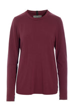 Load image into Gallery viewer, A refined jersey blouse designed with a timeless high neckline and an elegant silhouette. Made from soft ECOVERO™ jersey, it combines everyday comfort with a polished look that works effortlessly across seasons. The extra-long slim sleeves create a sophisticated expression, while signature grosgrain ribbons at the neck and cuffs add subtle HSCPH details. A versatile wardrobe piece designed for both relaxed and more dressed-up styling.
Wear it with lounge trousers on slower days at home or pair it with jeans