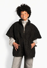 Load image into Gallery viewer, A modern quilted cape crafted in a signature Hést pattern, featuring a relaxed, voluminous silhouette. Designed with a high stand collar and half-zip front for versatility, it combines lightweight warmth with a distinctive textured surface and effortless, contemporary appeal.