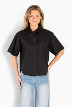 Load image into Gallery viewer, A relaxed short-sleeve shirt designed with a clean, modern silhouette. Crafted from soft cotton, it features a classic collar, a concealed button placket, and a chest pocket with a subtle HÉST detail. The slightly boxy fit and soft drape create an effortless look that works equally well styled with denim or tailored pieces. A versatile wardrobe essential with understated elegance.