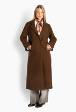 Load image into Gallery viewer, Mathea is a long wool-blend coat with a clean silhouette and a soft, structured drape. The defined collar, angled welt pockets and simple front closure create a timeless look. A high back vent with decorative buttons adds a distinctive detail, while a subtle Hést logo detail at the hem completes the design.