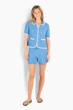 Load image into Gallery viewer, A short-sleeved knit cardigan designed with a clean, slightly relaxed silhouette and a soft, textured feel. Crafted from organic cotton, it offers breathable comfort with a refined finish. Featuring a classic collar, front closure, and contrast trim for a subtle, graphic touch. Finished with front patch pockets that add a structured, decorative detail. Style it with the matching shorts for a coordinated, modern summer look.