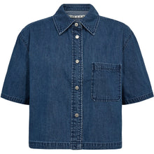 Load image into Gallery viewer, Malika Uta is a short-sleeved button-up shirt in soft cotton denim, cut in an oversized silhouette for a relaxed, boxy look. The wide sleeves, classic collar and chest pocket add a timeless utility feel, while the cropped length makes it perfect for high-rise jeans or layered looks. Wear it solo or pair it with the Malika pants for a coordinated denim set.
Size &amp; Fit:
• Oversized fit
• Boxy silhouette
• Cropped length
• Wide short sleeves
Details:
• Mid blue denim wash
• Chest pocket
• Button closure