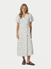 Load image into Gallery viewer, Wrap dress in a natural linen blend in a dotted print. The dress has a tie band and wraps around the waist. The sleeves are short and puffed. The model is wearing a size 36.