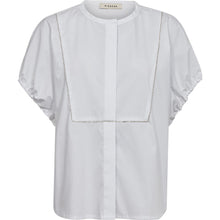 Load image into Gallery viewer, The Dahlia SS Shirt is crafted in clean white poplin, it features a relaxed silhouette with soft volume in the short sleeves, finished with subtle elasticated cuffs.
A tonal bib-inspired front is elevated by delicate chain embellishment, adding a quiet statement to the otherwise minimal design.
Size &amp; Fit
• Relaxed fit
• Hip length
• Short sleeves with volume
• Straight silhouette
Details
• Round neckline
• Concealed front button closure
• Decorative chain detailing at front
• Elasticated sleeve hems