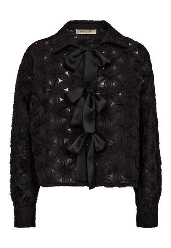 he Lexie 3D Chiffon Tie Shirt is a bold statement in texture and femininity. Featuring sculptural chiffon flowers and three oversized satin bows, this sheer button-up reimagines romantic tailoring with a graphic edge.
The crisp collar and tailored cuffs provide contrast to the playful silhouette, making it a standout choice for both day-to-night dressing and elevated layering.
Size & Fit
• True to size
• Straight fit
• Cropped length
Details
• Semi-sheer chiffon with 3D floral texture
