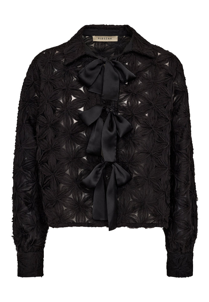 he Lexie 3D Chiffon Tie Shirt is a bold statement in texture and femininity. Featuring sculptural chiffon flowers and three oversized satin bows, this sheer button-up reimagines romantic tailoring with a graphic edge.
The crisp collar and tailored cuffs provide contrast to the playful silhouette, making it a standout choice for both day-to-night dressing and elevated layering.
Size & Fit
• True to size
• Straight fit
• Cropped length
Details
• Semi-sheer chiffon with 3D floral texture
