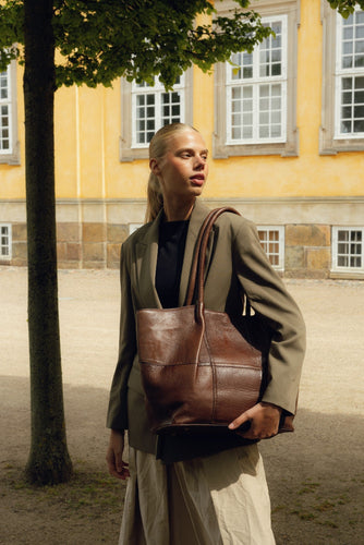 The Mane Big is a stylish workbag designed with elegance and practicality in mind. It features comfortable shoulder straps and a beautiful ruched design running down the front, adding a soft and luxurious touch to its look. The bag has a structured base, allowing it to stand upright on its own. Inside, you'll find a spacious main compartment with plenty of room for your everyday essentials — perfect for life on the go.